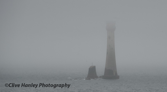 Eddystone lighthouse almost hidden in the mist. The stub of Smeatons Tower at its side.