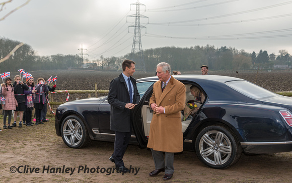 Prince Charles exits his limousine while the farmer who donated the land in order to create the footpath around his field looks on.