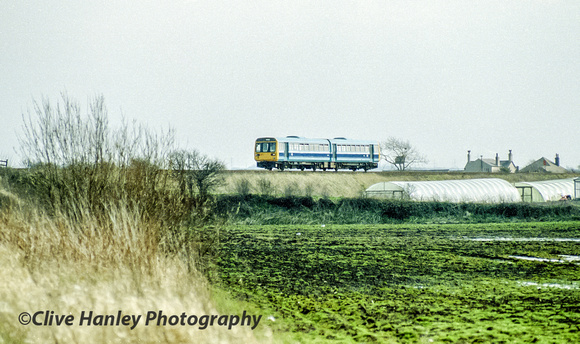 A Class 142 BREL/Leyland "Pacer" 2 car "Nodding Donkey" heads north between Burscough and Rufford in West Lancashire.