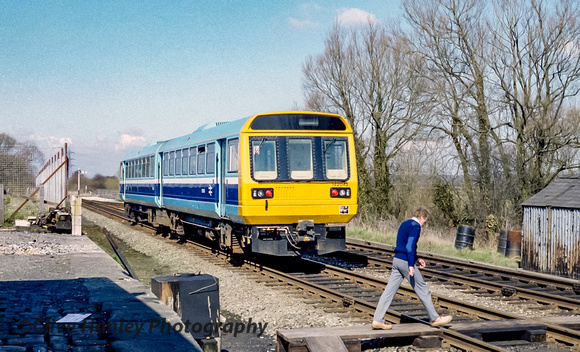 As unit 142042 departs the bobby crosses the tracks back to the signal box