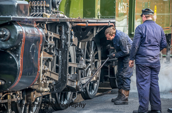 With a chap under the loco with a water hose pipe the rocking grate is activated to throw out the ashes which can be seen between the wheels.