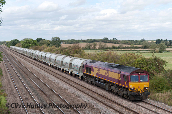 A Class 66 no 66201 moves slowly south with a cement wagon working.