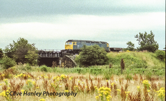 Class 47 no 47137 stands on the track just south of Maghull adjacent to the Leeds-Liverpool canal bridge with a PW train.